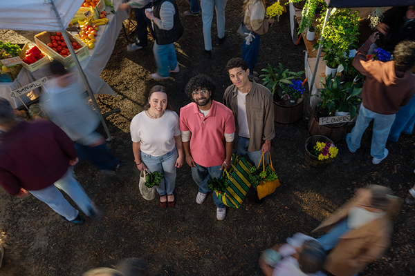 Three people with shopping bags at a food market