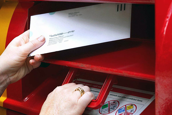 A person deposits a ballot pack in a mailbox