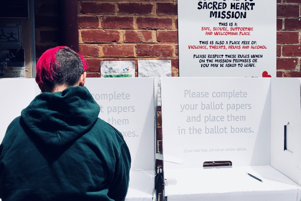 Person at voting booth filling out a ballot paper