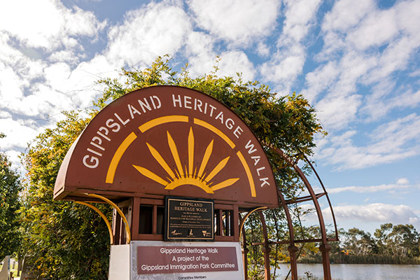Gippsland Heritage Walk logo and sign in front of an archway covered in greenery