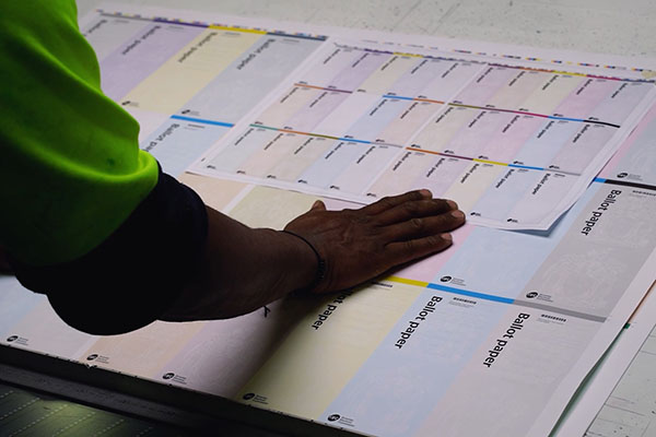 A hand is placed on a ballot paper.