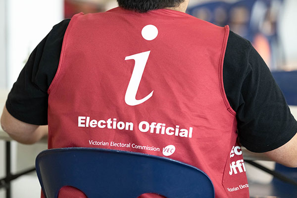 An election official in a burgundy VEC vest