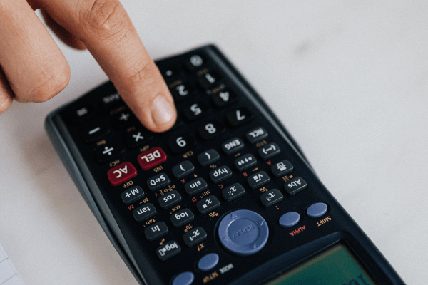 A hand pressing a button on a calculator