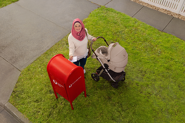 A person with a pram at an Australia Post mailbox